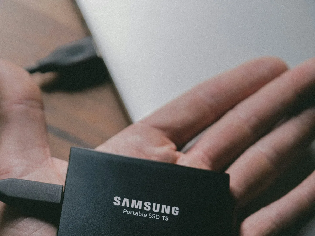 A Samsung portable SSD drive held in an open hand before connecting it for backup