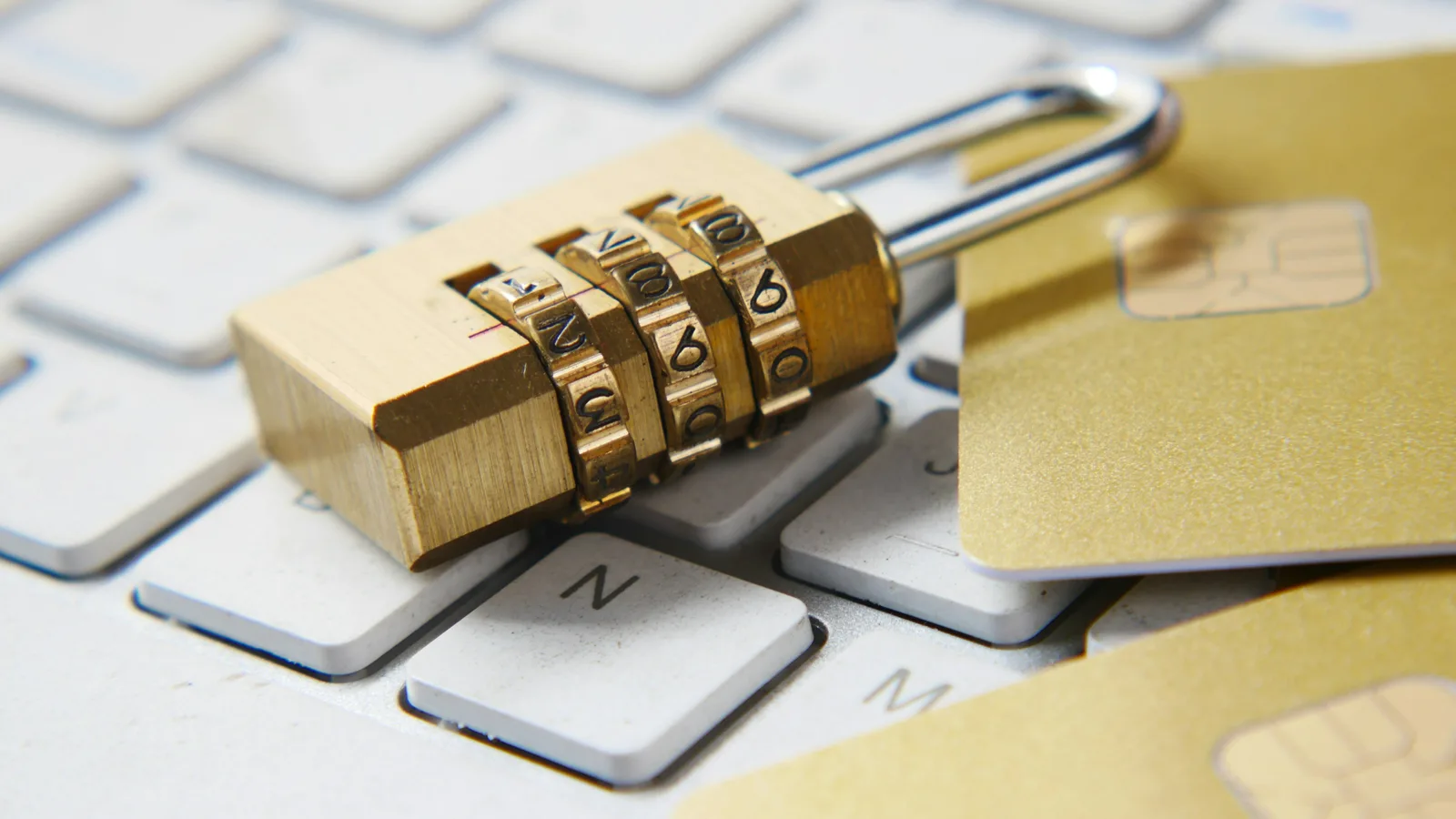 A gold combination padlock resting on a computer keyboard