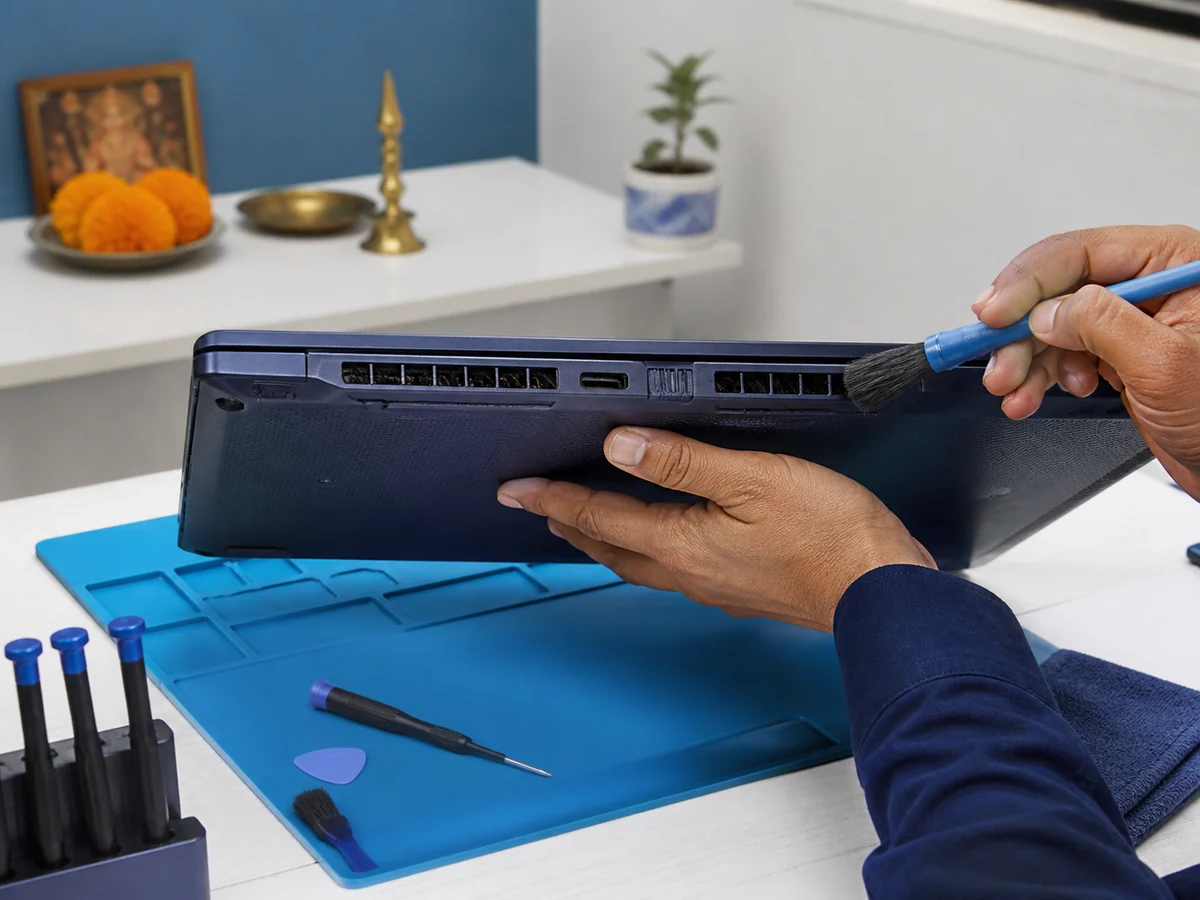 Professional hands inspecting and gently brushing the exterior cooling vents of a laptop