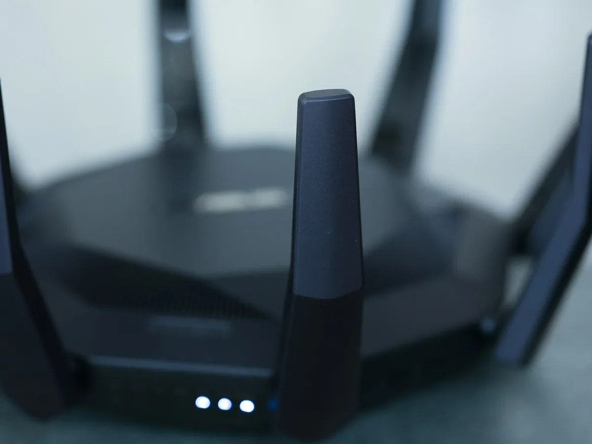 Close-up of a black wireless router with its antennas raised on a desk